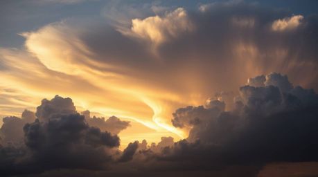 Experience the breathtaking beauty of high-contrast, low-key lighting illuminating graceful thunderstorm clouds at sunset.  D