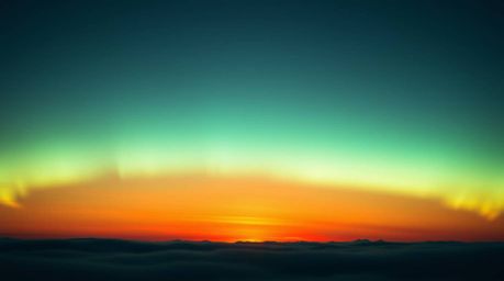 A captivating image of the Northern Lights emerging over a vibrant sunset sky.  The scene showcases a gentle contrast between