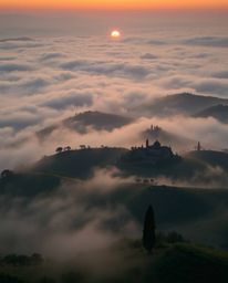 Fine art photograph: Overhead bird's-eye view of a sunset over misty Tuscan hills. Soft contrast and saturation. Associated P