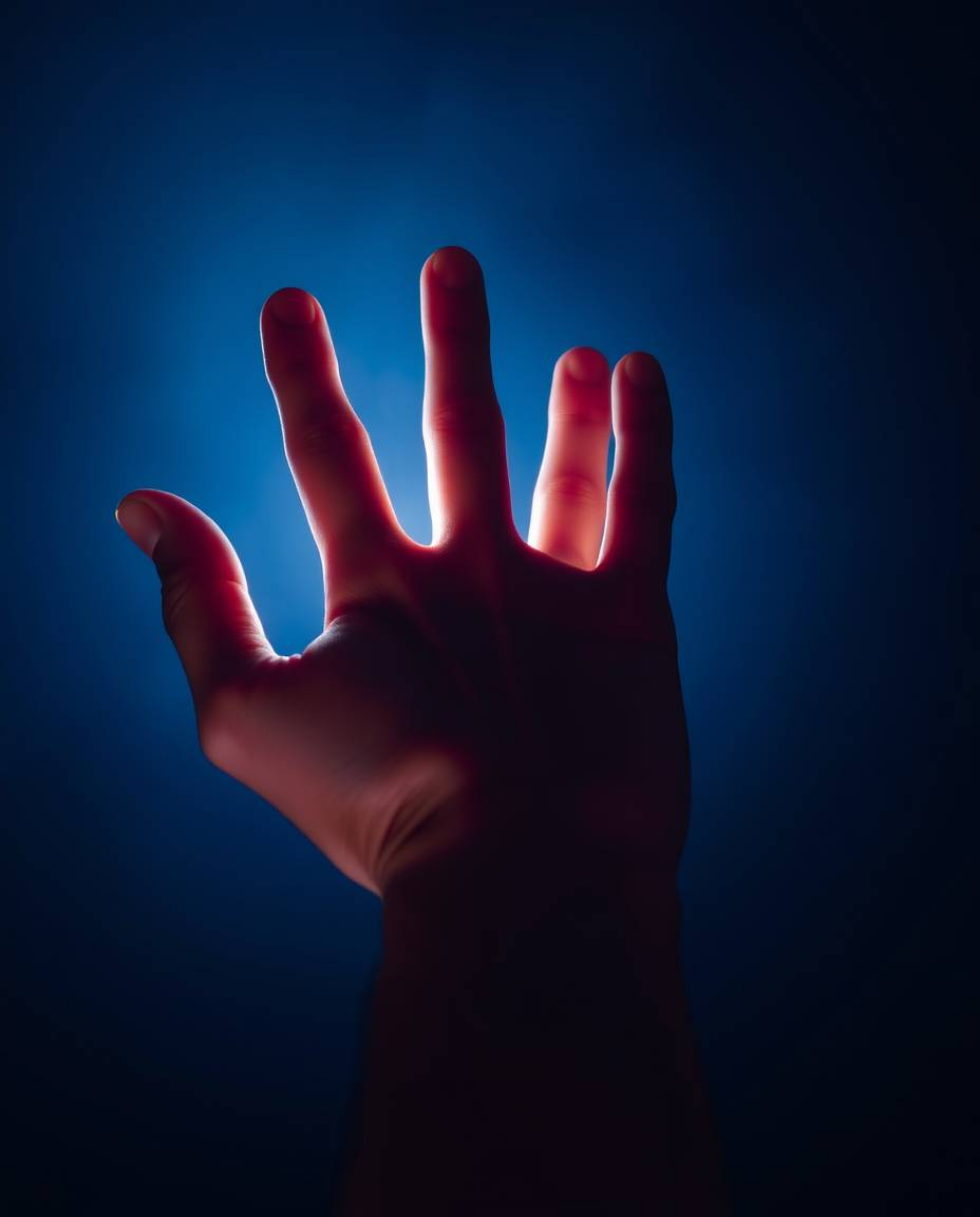 A captivating image depicts a hand emerging from darkness, reaching towards a source of light.  Rendered in cool colors with 