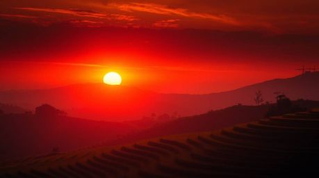 Experience a warm and dramatic cinematic sunset over stunning rice terraces. This film-like composition features rich reds, o