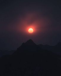 Experience a high alpine peak sunset through an eerie and creepy atmosphere, dominated by dark tones and unsettling details. 