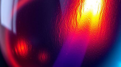 This captivating image showcases a close-up detail of a glass object reflecting smooth gradient textures in a symphony of ele