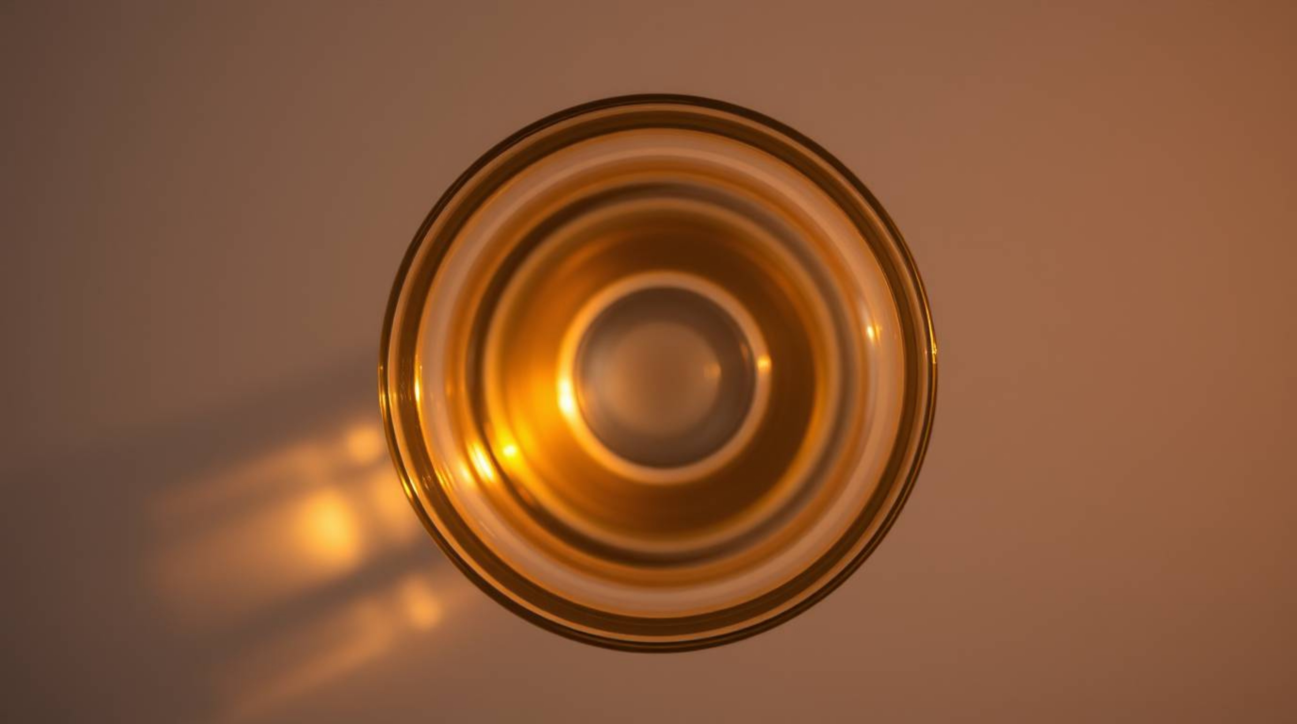 An overhead bird's-eye view captures a stunning glass object reflecting smooth gradient textures under the warm golden hour l