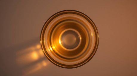 An overhead bird's-eye view captures a stunning glass object reflecting smooth gradient textures under the warm golden hour l