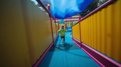 Capture a dramatic slow-motion run through a playground with a high angle perspective, utilizing cool colors like blues, gree