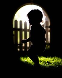 A captivating photograph captures a child silhouetted against a bright light source, in the midst of discovering a magical po
