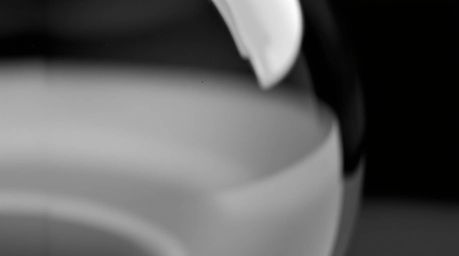 A captivating close-up black and white photograph showcasing a timeless glass object reflecting smooth gradient textures. Emp
