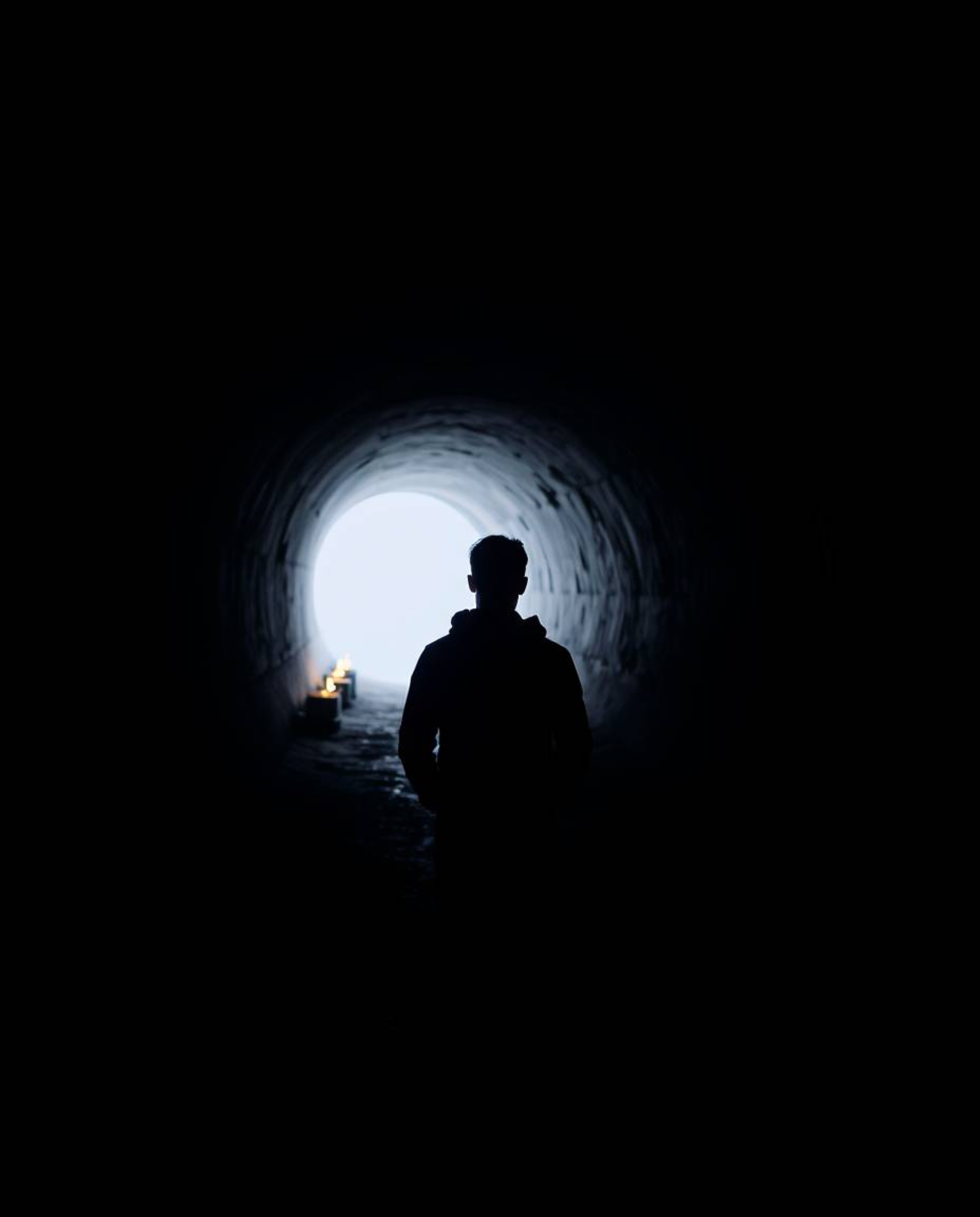 A captivating image depicting a person standing at the edge of a tunnel, their gaze drawn towards a distant light source. The