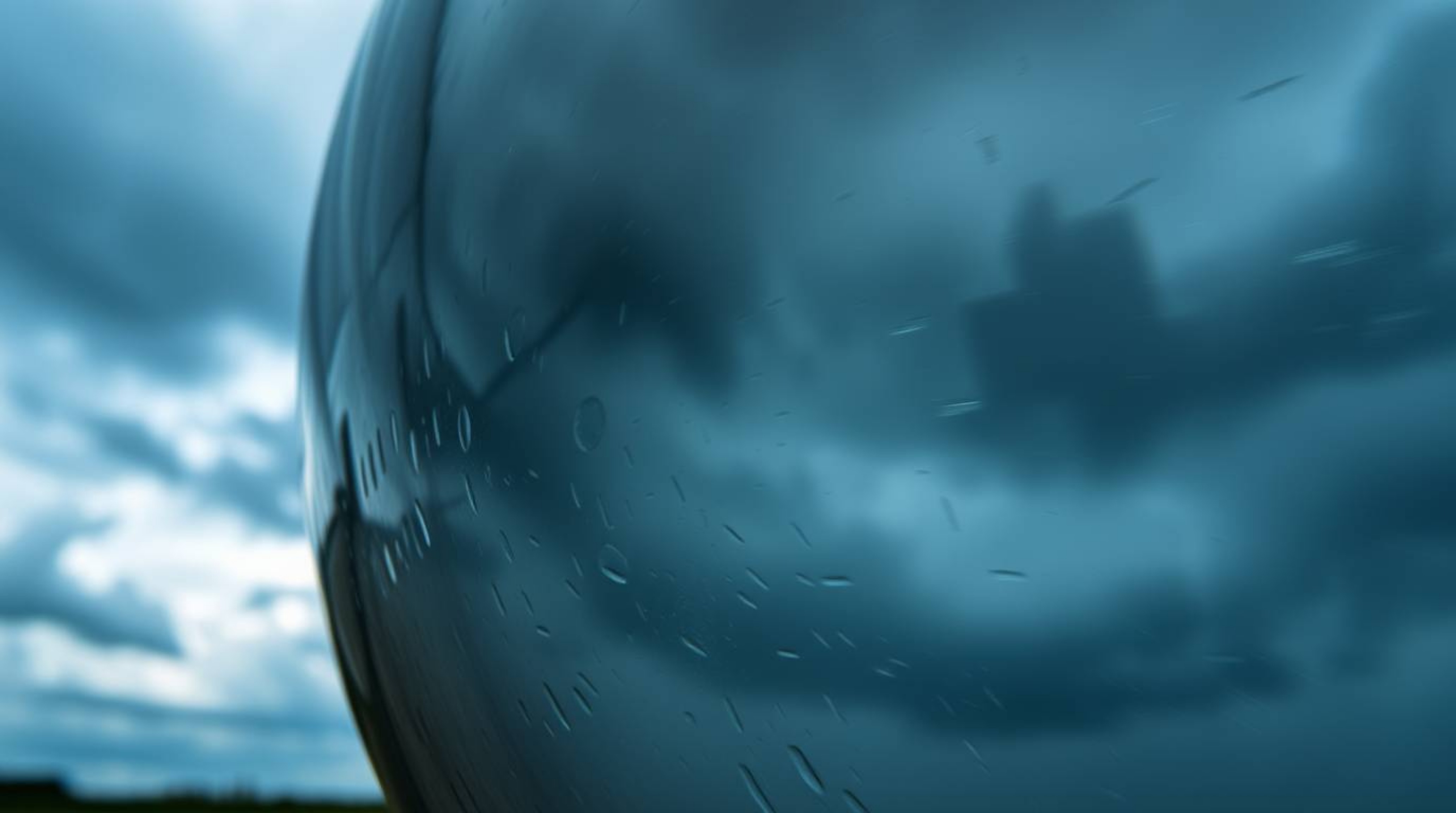 A captivating long-exposure photograph showcases a glass object reflecting the intense drama of a stormy sky.  Smooth gradien
