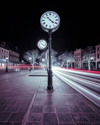 This surreal infrared photograph captures an empty town square dominated by ticking clocks. The long exposure technique beaut