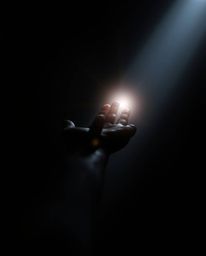 A captivating image depicts a hand emerging from intense black darkness, reaching towards a radiant light source. This high-a