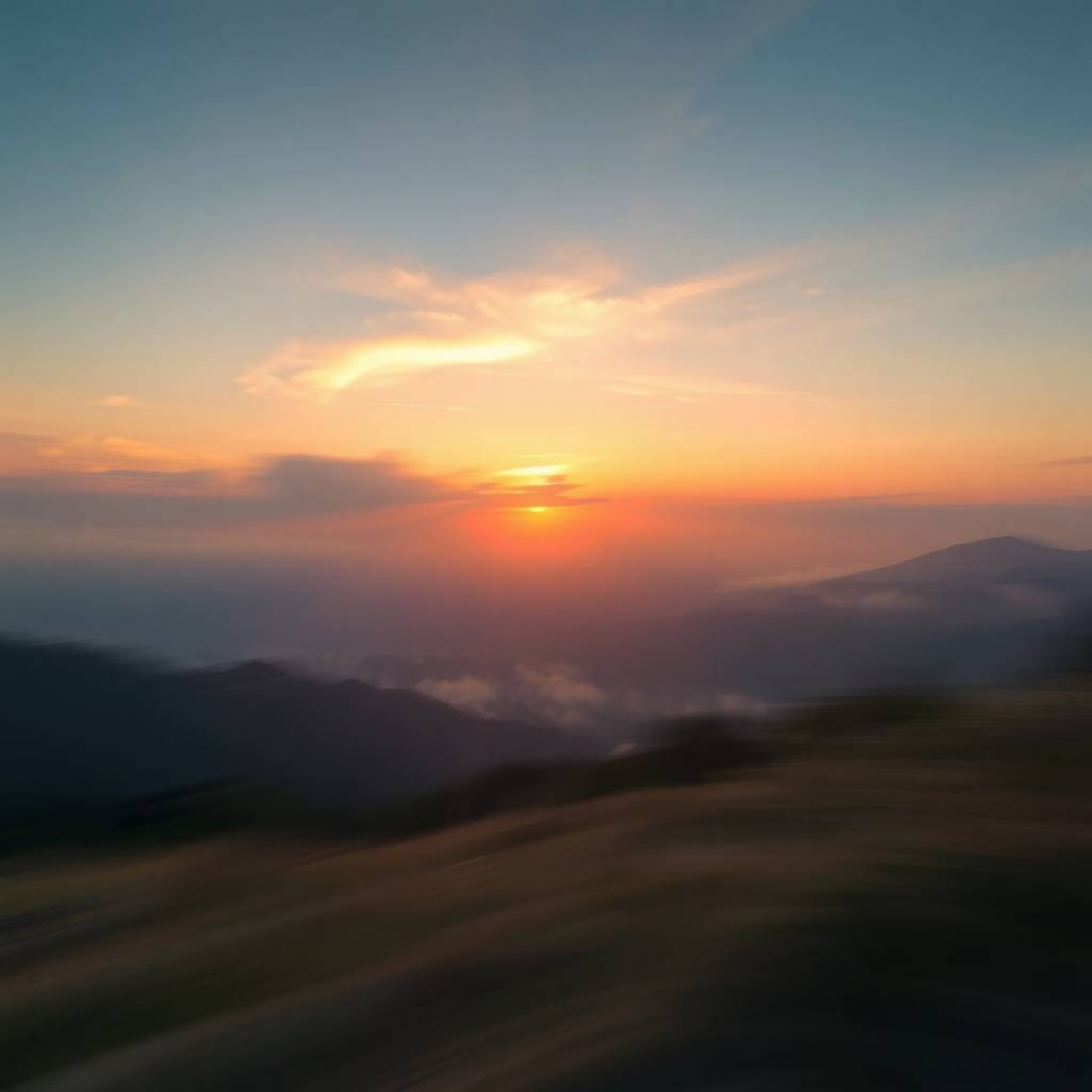 Capture the serene beauty of a dreamlike sunset over a quiet mountain valley with blurred motion and gentle color contrasts. 