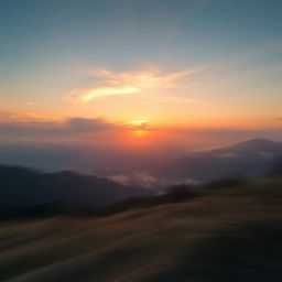 Capture the serene beauty of a dreamlike sunset over a quiet mountain valley with blurred motion and gentle color contrasts. 