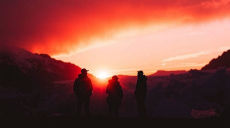 Experience the serene beauty of a sunset over icy glaciers in the polar region. Silhouetted figures stand in stark contrast a