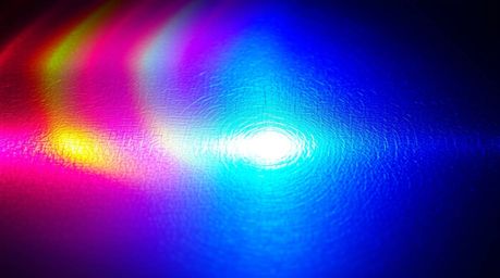 This captivating light art piece showcases an iridescent gradient texture on a metallic surface. Vibrant color shifts create