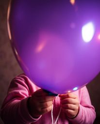 A captivating close-up photograph features a child holding a balloon, creatively illuminated with abstract light patterns. Th
