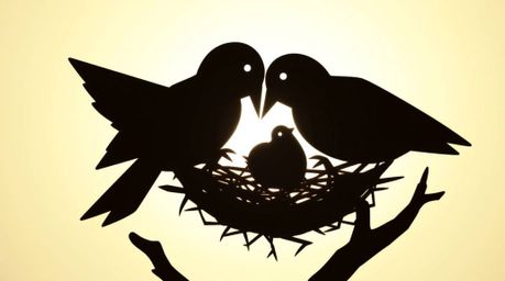 Two cartoon birds meticulously construct their nest in a charming, classic animation style, presented as a striking silhouett