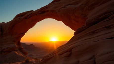 Capture the breathtaking beauty of a desert sunset framed by a natural rock arch. This high-resolution stock photo showcases 