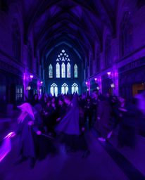 A captivating long-exposure photograph showcasing a magical school teeming with young wizards, awash in deep ultraviolet hues