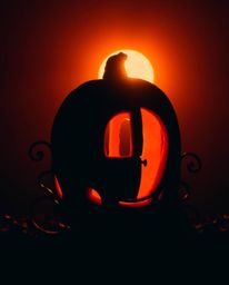 A captivating image of a silhouetted pumpkin magically transforming into a carriage, bathed in warm, dramatic lighting. Reds,