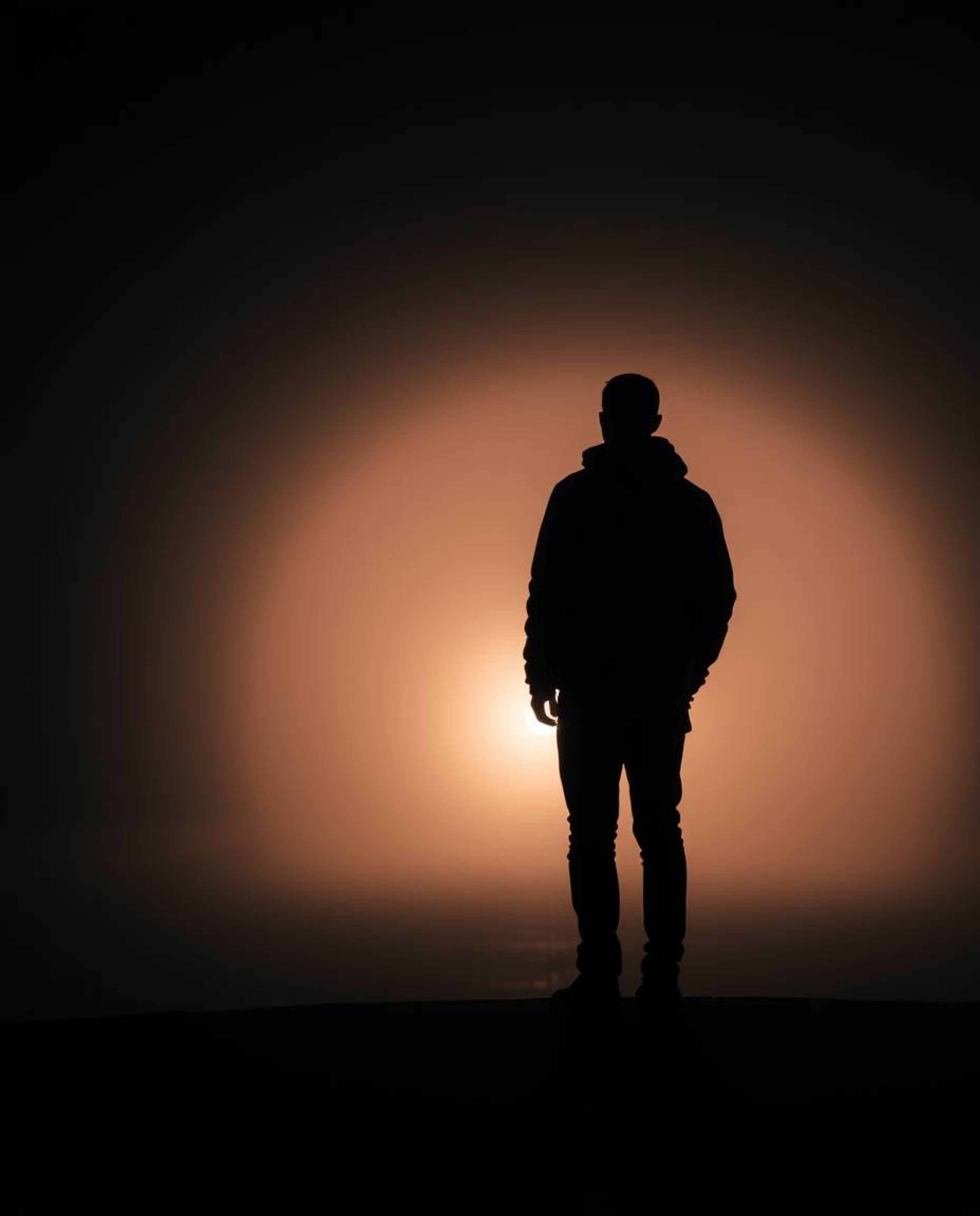 A professional fine art photograph capturing a person standing at the edge of a tunnel, gazing towards a light source within 