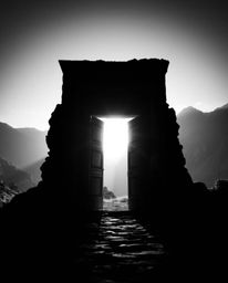 This captivating image showcases an ancient doorway etched with glowing runes, silhouetted against a majestic mountainside.  