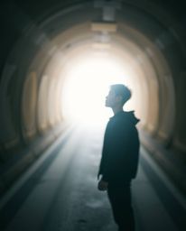 A captivating image depicting a person at the tunnel's edge, gazing towards a beckoning light. Rendered in gentle, soothing p