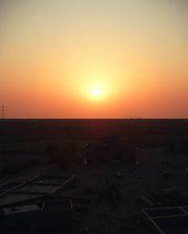 A captivating sunrise illuminates a war-torn landscape, distinctly split to showcase bold areas juxtaposed with a hazy backgr