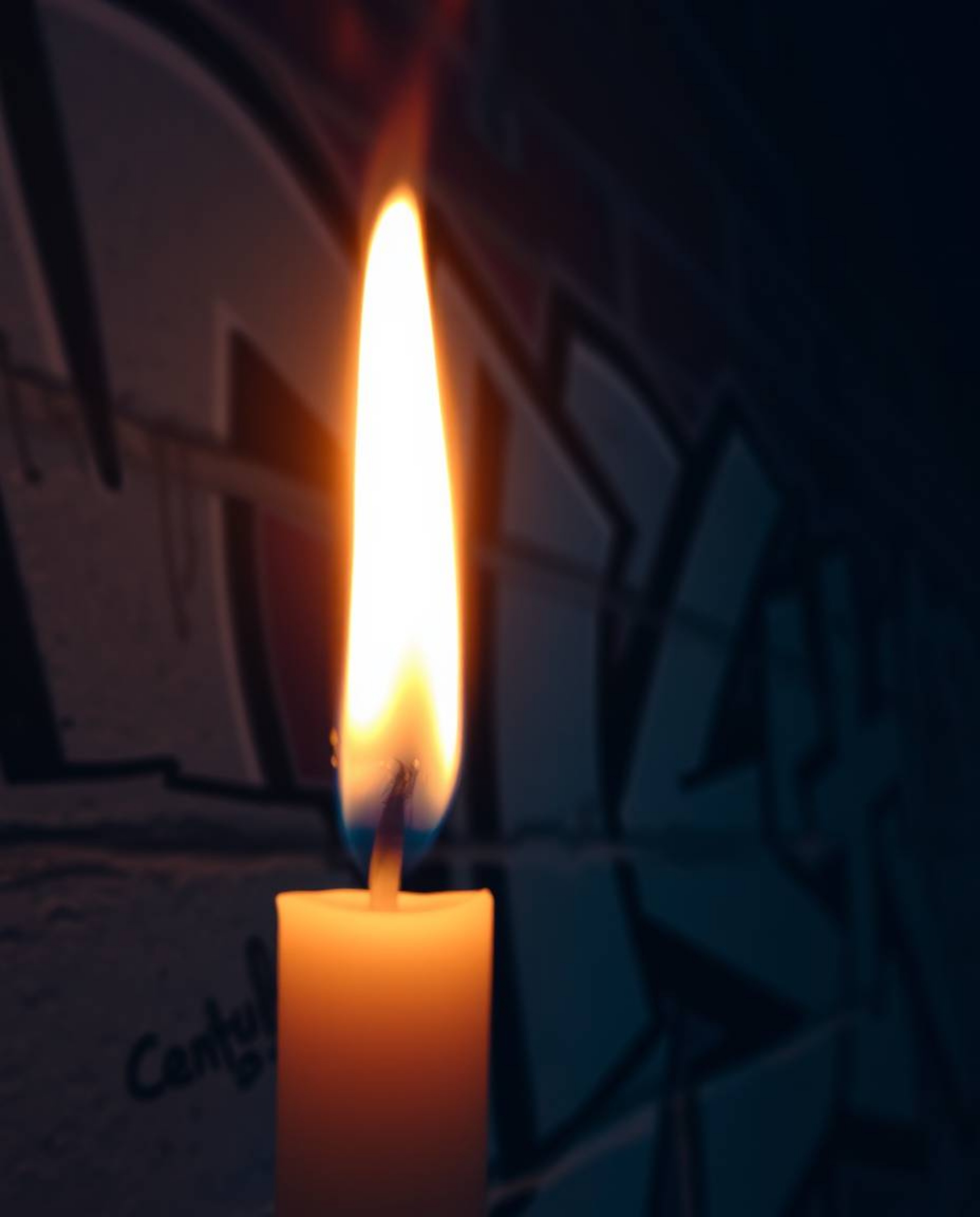 A close-up shot showcases the vibrant graffiti splashes adorning a textured brick wall, bathed in the warm, flickering light 