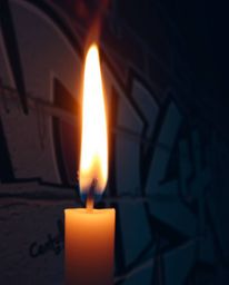 A close-up shot showcases the vibrant graffiti splashes adorning a textured brick wall, bathed in the warm, flickering light 