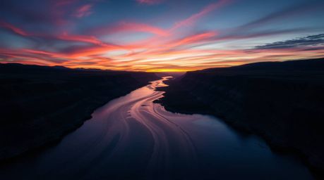 A mesmerizing image capturing a river delta awash in the radiant hues of twilight, presented from a distinctive low-angle per