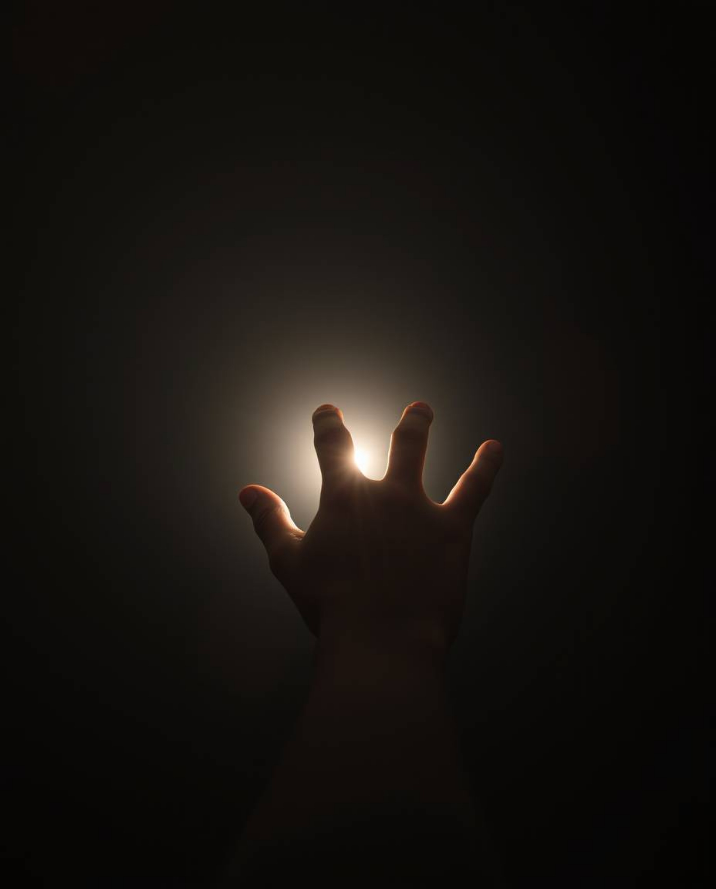A high-resolution stock photo depicting a hand reaching towards a light source from darkness.  The image utilizes a natural e