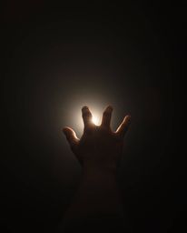 A high-resolution stock photo depicting a hand reaching towards a light source from darkness.  The image utilizes a natural e