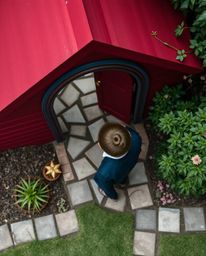 A sophisticated child, elegantly posed, stumbles upon a magical portal hidden within the details of their backyard. Captured