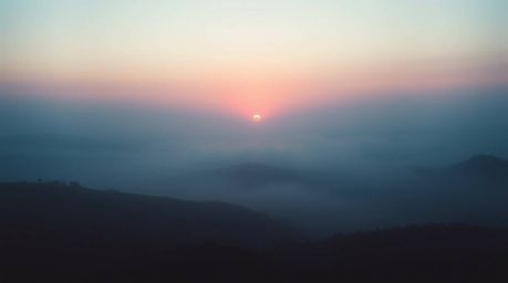 A breathtaking soft cinematic image capturing fog-covered hills bathed in the warm hues of sunset. The scene is rendered in c