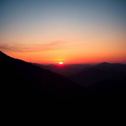 This high-resolution stock photo captures a breathtaking sunset over a serene mountain valley, presented in a dramatic cinema