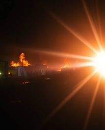 Experience a scene of intense chaos and vibrant destruction with this jet black photograph. A city engulfed in flames, people