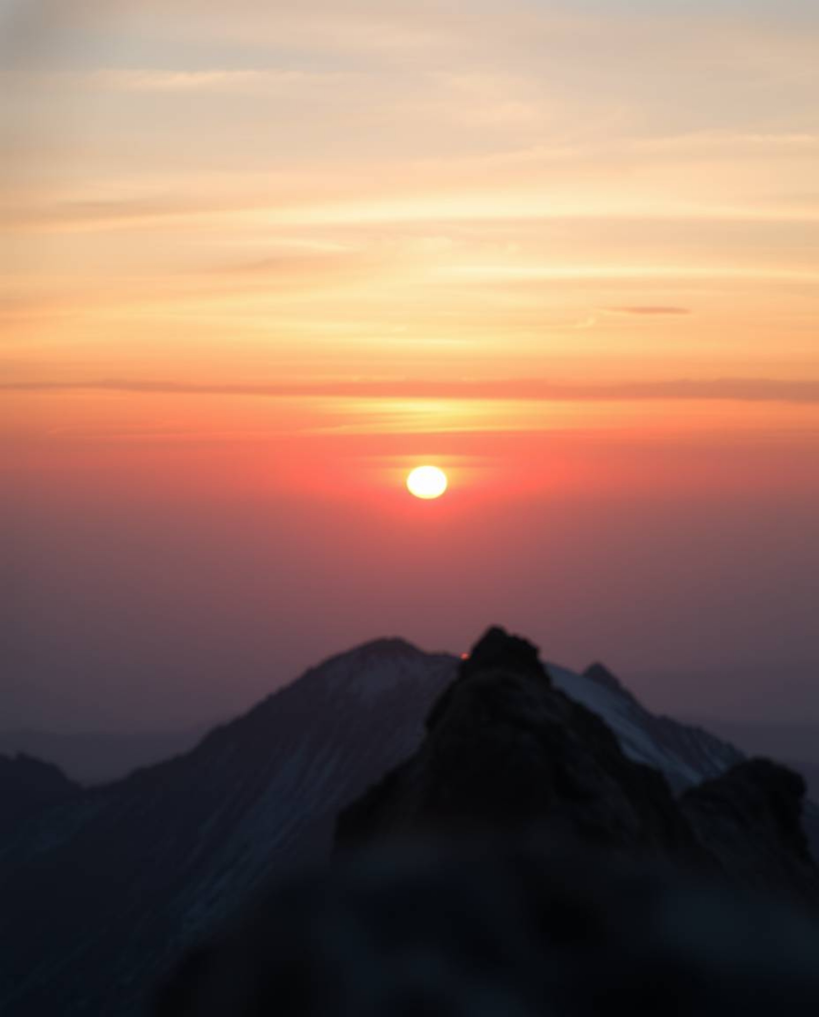 This is a tight close-up shot capturing a mystic and enchanting sunset as viewed from a high alpine peak. The composition emp