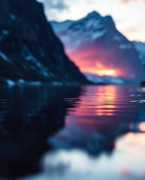 A tight close-up shot captures the reflection of a sunset in a glassy fjord, distinguished by its rich burgundy and deep blue