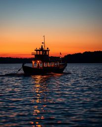 A boat drifting on a lake at sunset, photographed with precise architectural color, emphasizing sharp lines, detailed structu