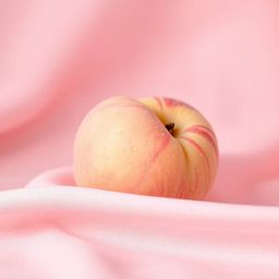 A calming ASMR close-up features a soft, blushing pink peach delicately resting on silky pastel pink fabric. Dew-like condens