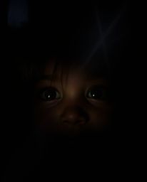 Strong, hard light illuminates adorable, cute eyes with charming features, creating direct and harsh shadows as they watch fr