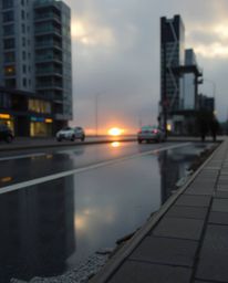 A candid street photograph depicting a glassy fjord reflecting a sunset, imbued with a soft cinematic haze. This image captur