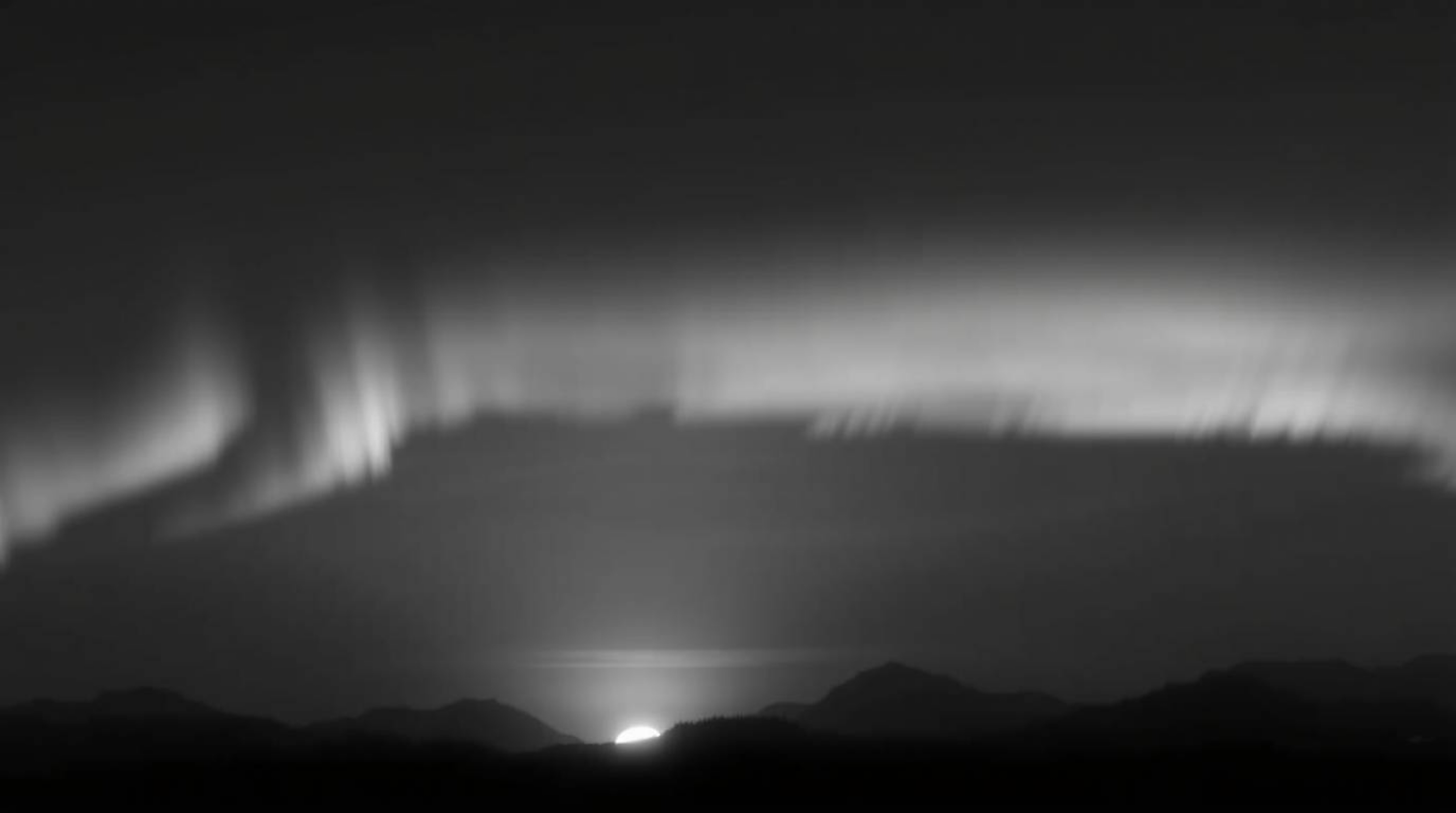 Capture the ethereal beauty of the Northern Lights dancing above a breathtaking sunset sky in this classic black and white ph