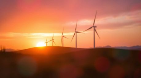 Capture the mesmerizing beauty of a sunset behind a row of wind turbines on a hill, showcasing iridescent reflections and a s