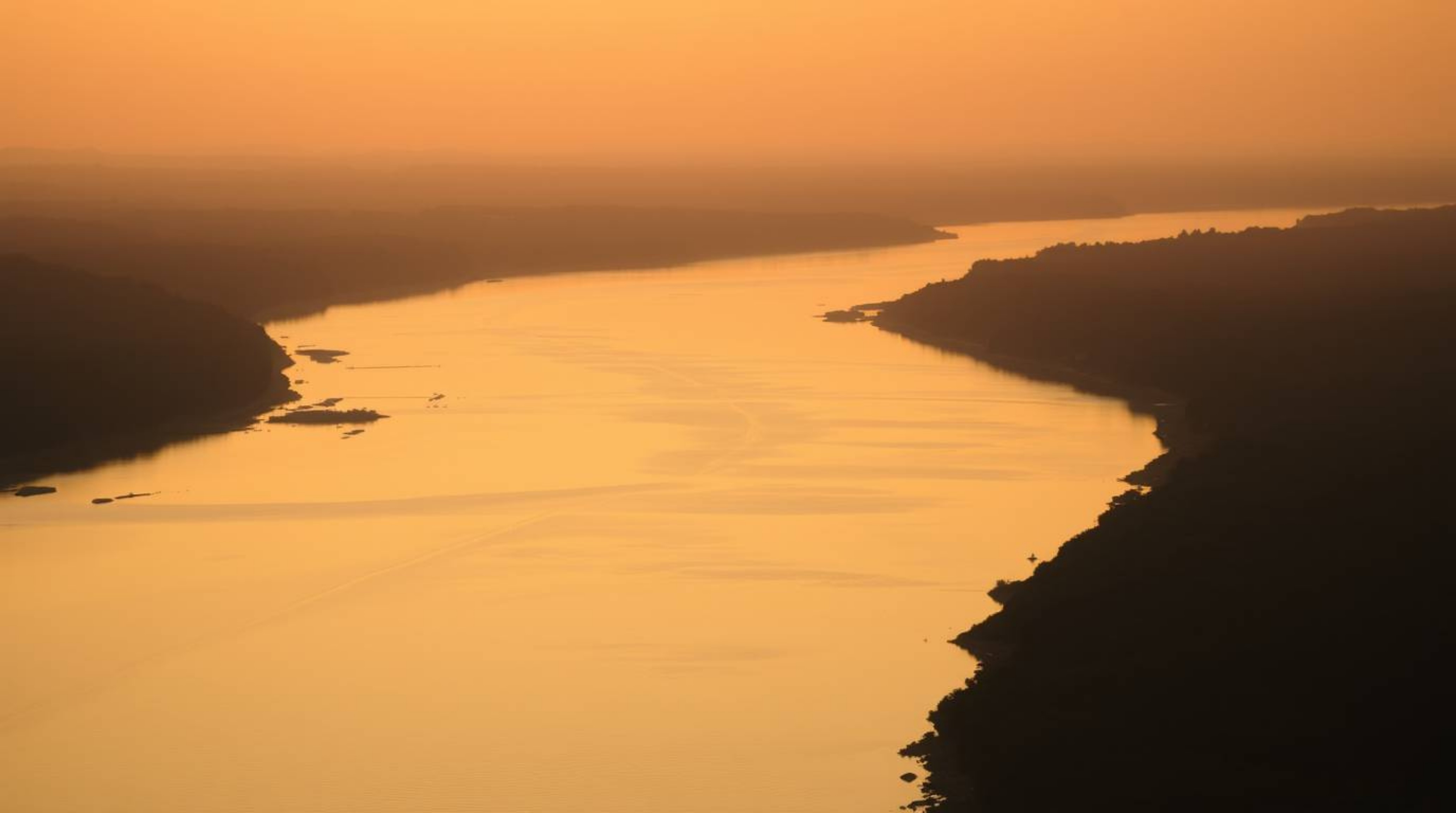 Experience the serene beauty of a river delta bathed in the warm glow of golden hour light.  Imagine soft, twilight colors pa