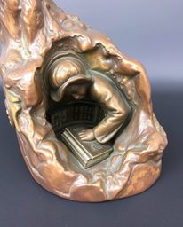 This cast bronze sculpture captures a poignant moment: a person discovering a hidden underground library. The sculpture's sur