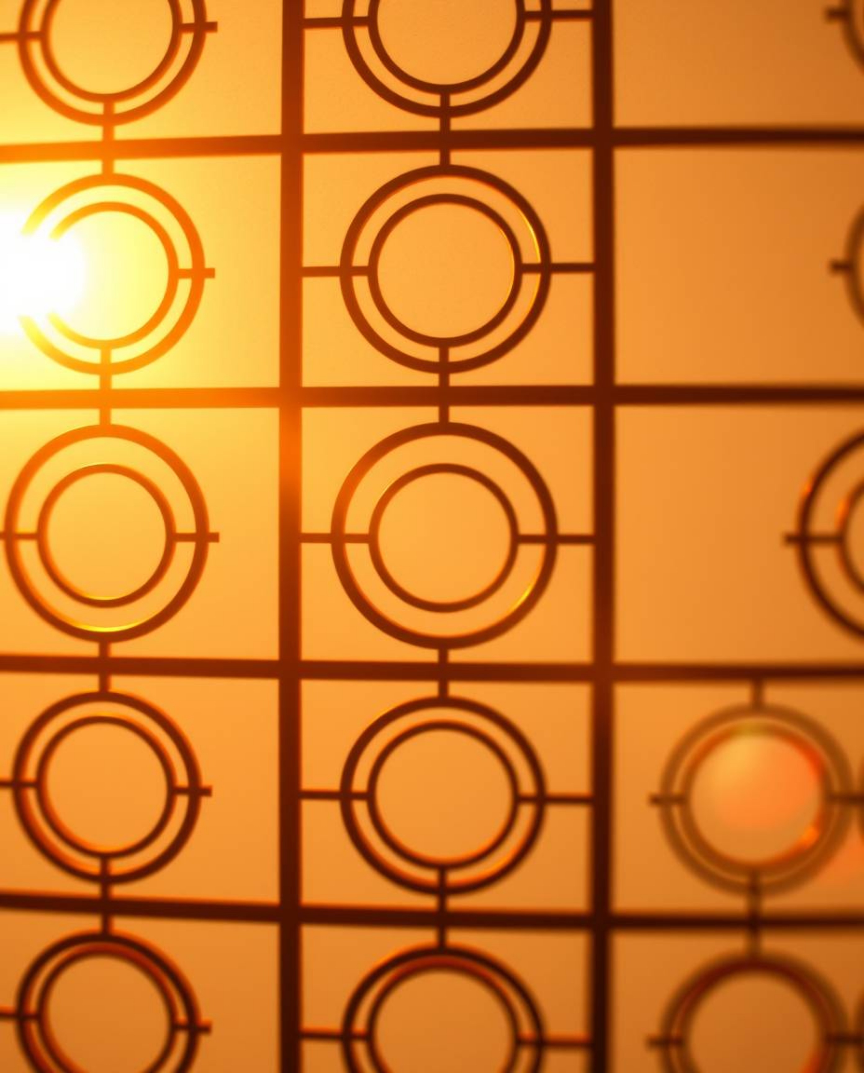 A close-up shot bathed in warm golden hour light showcasing a minimalist geometric pattern in the Bauhaus style. The soft lig