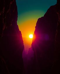 An intensely lit scene captures a sunset illuminating sandstone cliffs within a canyon, where the landscape is dominated by d